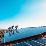 a professional photography of a rooftop solar power installation with MSM Solar LLC branding, featuring a group of technicians installing solar panels on a residential home in a sunny, clear-sky landscape. The image showcases the company's expertise, attention to detail, and commitment to providing comprehensive solar services. The foreground depicts the technicians at work, the middle ground shows the solar panels being installed, and the background features a scenic view of the neighborhood. The lighting is natural and evenly distributed, creating a warm and inviting atmosphere. The lens captures a wide, high-angle perspective to emphasize the scale and scope of the solar service operation.
