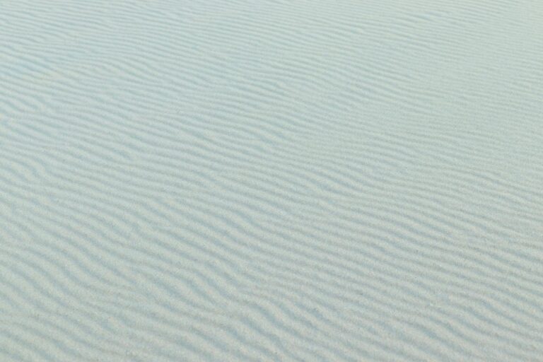 Fine rippled sand pattern under a bright sky, capturing the essence of a tranquil desert scene.
