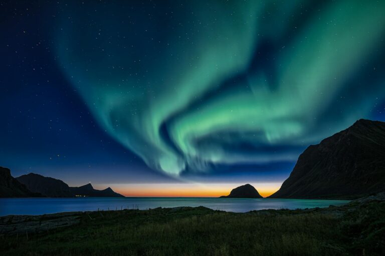 Breathtaking view of the Northern Lights illuminating the Lofoten Islands in Norway at twilight.