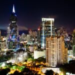 Illuminated skyscrapers under a moonlit sky in Panama City's vibrant urban landscape.