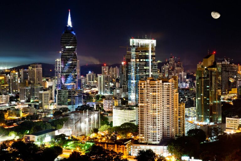 Illuminated skyscrapers under a moonlit sky in Panama City's vibrant urban landscape.