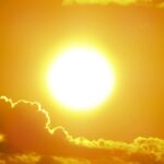 A stunning view of the golden sun shining through clouds at sunset, casting a warm glow.