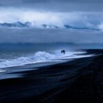 Moody seascape capturing crashing waves under a dramatic, cloudy sky.