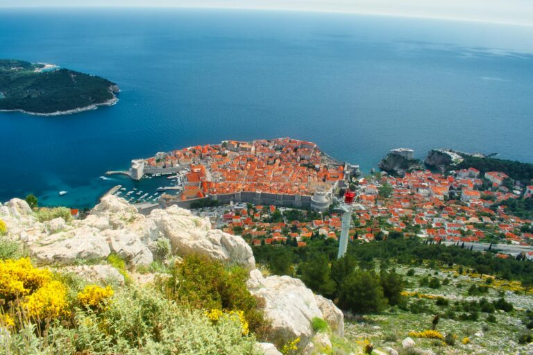Stunning aerial view of Dubrovnik's historic old town by the Adriatic Sea, showcasing vibrant red rooftops.