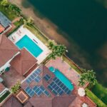 Top-down view of a Miami home with solar panels and pool near a lake.