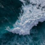 Aerial view of powerful ocean waves crashing against the rocks, capturing the essence of nature's strength.