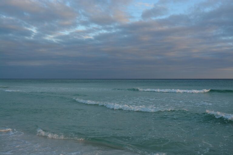 A serene view of gentle waves and a tranquil sea under a cloudy sky at Destin Beach, Florida.