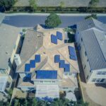Aerial view of suburban homes equipped with solar panels in a sunny neighborhood.