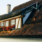 Close-up of a quaint house with a red brick roof, solar panels, and flower boxes.