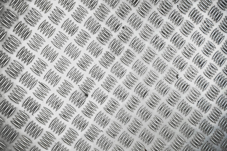 Close-up view of a silver metallic tread plate with a repeating checkered pattern.