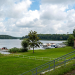 Idyllic view of a tranquil lake with docks, boats, and lush greenery under a cloudy sky.
