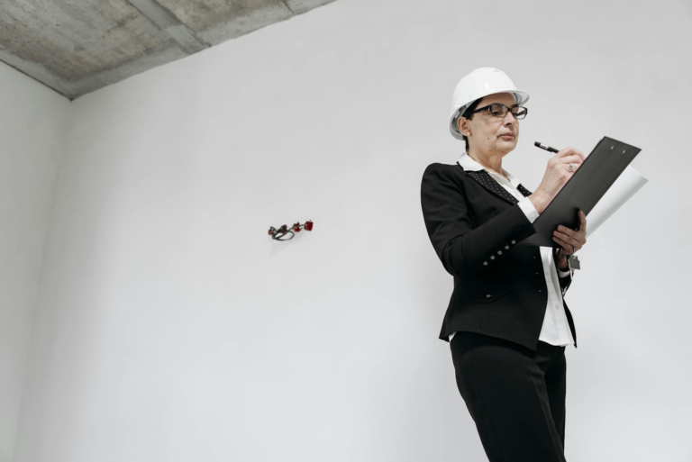 Businesswoman in formal attire with helmet inspecting a renovation project indoors.