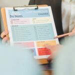 Close-up of hands holding a home inspection checklist clipboard for buyers.