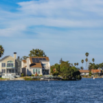 Charming waterfront homes with palm trees and solar panels reflecting in blue water.