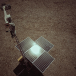 Aerial shot of a solar panel on a deserted landscape, reflecting sunlight.