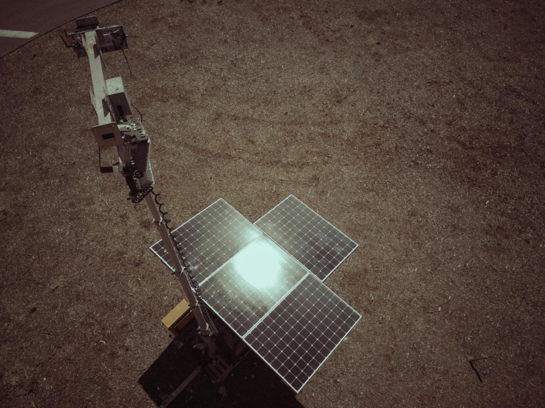Aerial shot of a solar panel on a deserted landscape, reflecting sunlight.