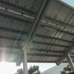 Close-up of solar panels on metal structure with sunlight filtering through, emphasizing sustainable energy.