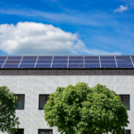 Energy-efficient building topped with solar panels and surrounded by lush trees.