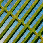 High-angle aerial shot of solar panels in a lush green field, located in Rockbeare, UK.