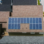 Drone shot of solar panels on residential roofs promoting eco-friendly energy solutions.
