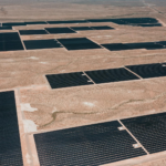 Drone shot of a large solar farm in a desert landscape, showcasing renewable energy infrastructure.