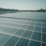 Rows of solar panels near a highway capture renewable energy under a clear sky.