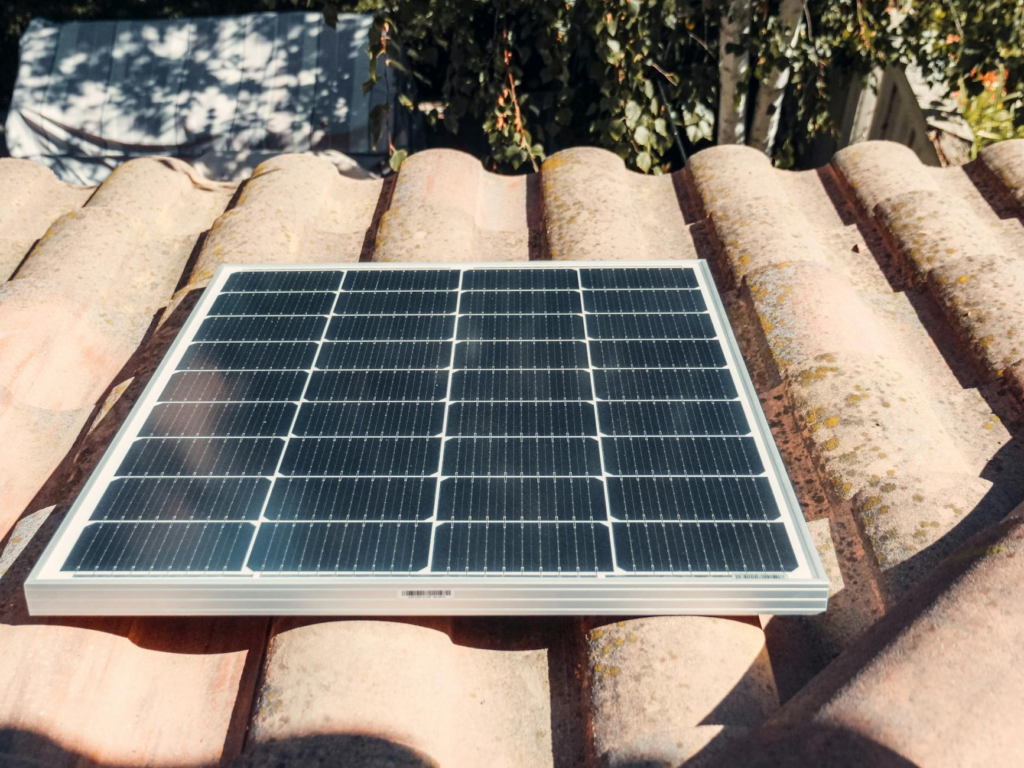 A single solar panel on a rustic tiled roof gleaming in sunlight. Eco-friendly energy.