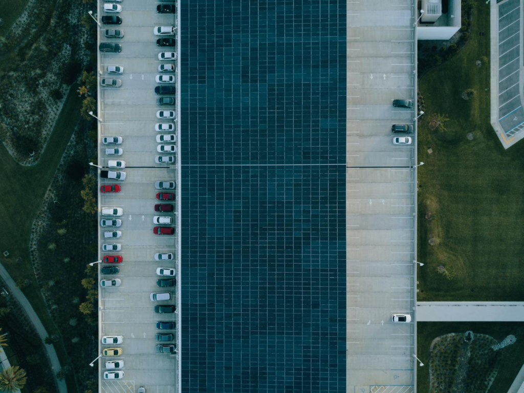 Top view of a parking lot with cars and solar panels, showcasing urban sustainability.
