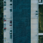Top view of a parking lot with cars and solar panels, showcasing urban sustainability.
