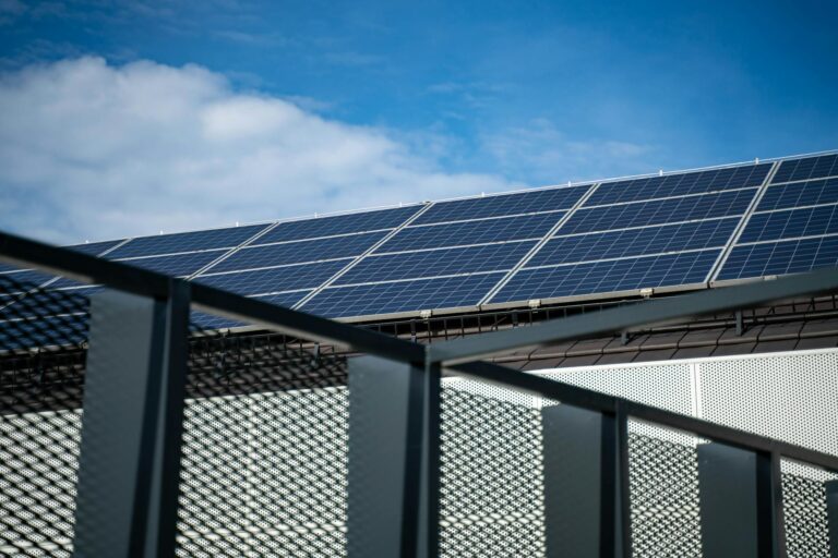 Close-up view of modern solar panels on a rooftop against a clear blue sky, representing clean energy.