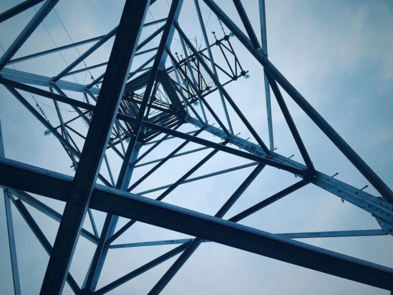 Low angle shot of a steel electricity tower against a clear sky.