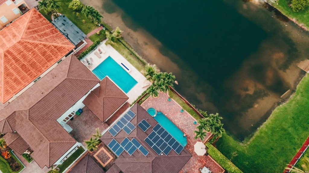 Top-down view of a Miami home with solar panels and pool near a lake.