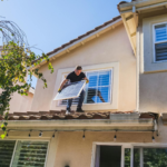 A solar technician installing panels on a house roof, emphasizing renewable energy.