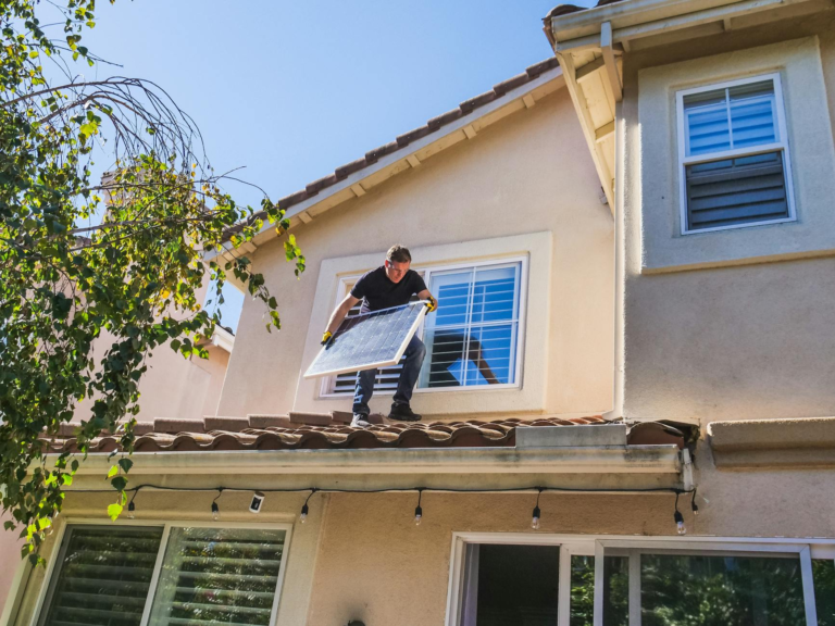 A solar technician installing panels on a house roof, emphasizing renewable energy.