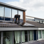 Technician working on installing solar panels on a residential rooftop during the day.