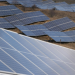 Aerial view of a large solar panel farm capturing sunlight in an open field.