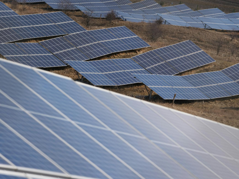 Aerial view of a large solar panel farm capturing sunlight in an open field.