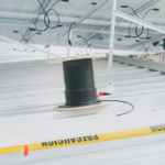 Coiled cable on a rooftop with solar panels, showcasing electrical installation for renewable energy.