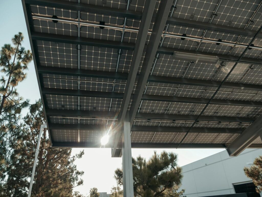 Low angle shot of solar panels with sun shining through, illustrating renewable energy concept.