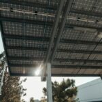 Low angle shot of solar panels with sun shining through, illustrating renewable energy concept.