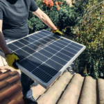 A worker installs a solar panel on a rooftop amidst lush greenery.