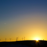 Silhouette of wind turbines against a vibrant sunset sky, capturing renewable energy theme.