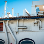 White building with chimneys and ventilation pipes on a clear day.