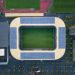 Drone shot of a modern stadium with solar panels and sports fields.