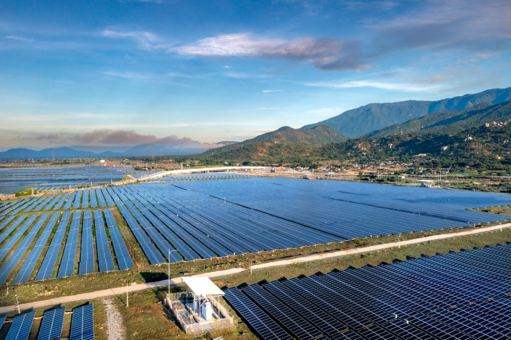 Expansive solar panels in a scenic landscape with mountains, demonstrating renewable energy efforts.
