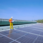 A solar technician inspects solar panels on a rooftop under a clear blue sky, promoting renewable energy.