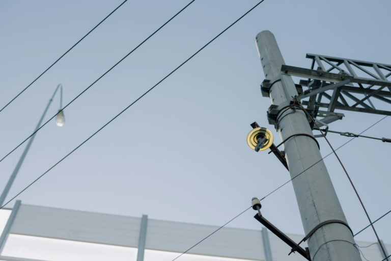 Utility pole with electrical wires and equipment against a clear blue sky, showcasing urban infrastructure.