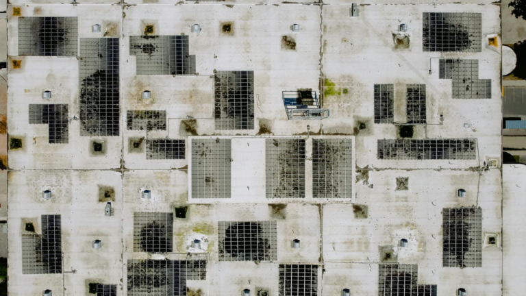 An industrial rooftop with solar panels, viewed from above, ideal for renewable energy concepts.