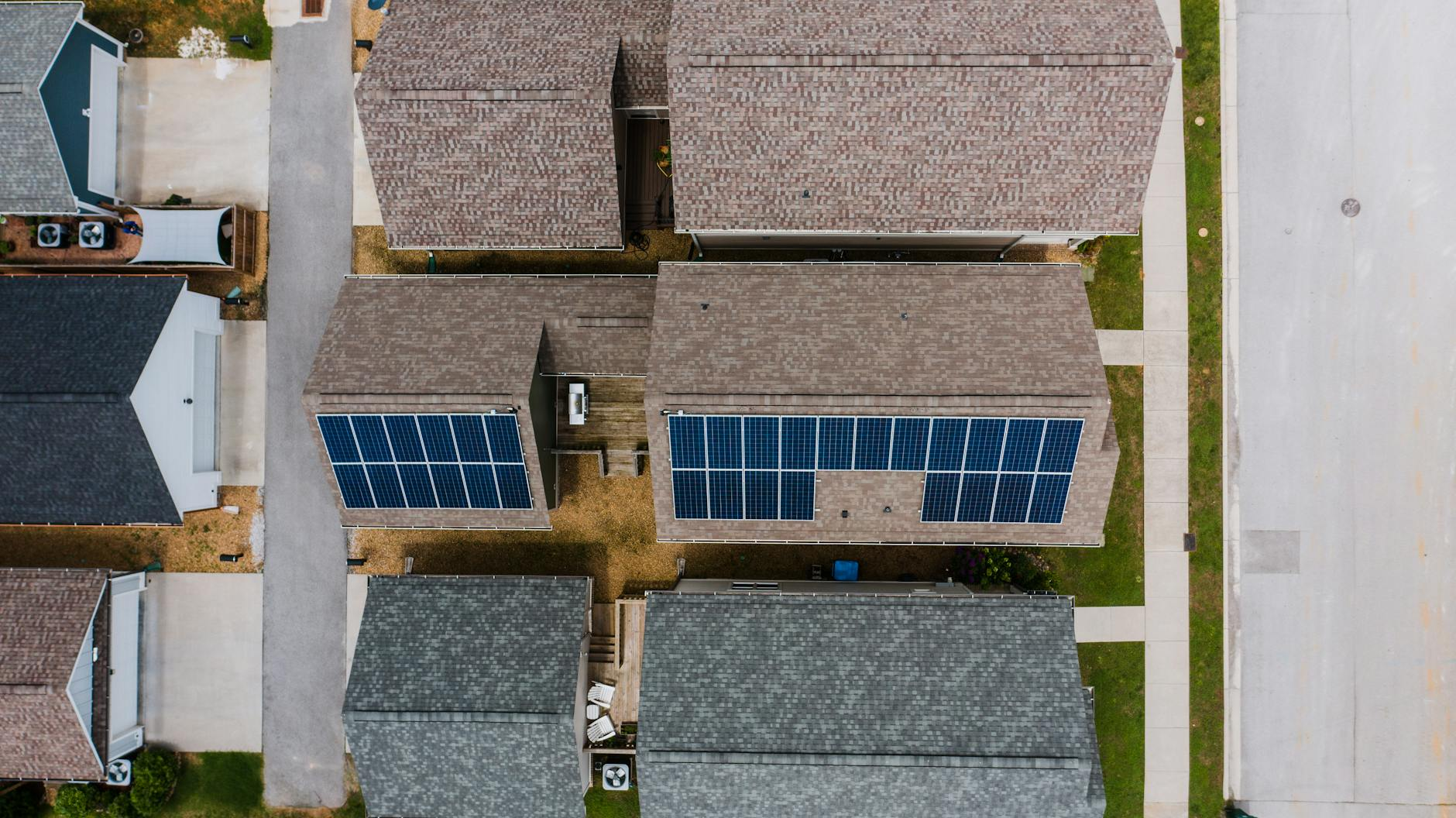 Top-down view of suburban houses featuring solar panels on roofs, showcasing renewable energy use.