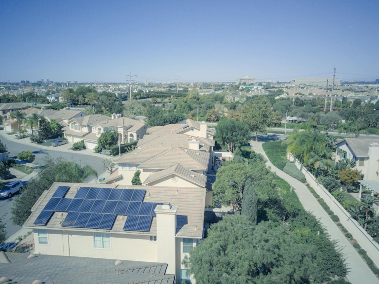 Aerial shot of a suburban neighborhood with solar panels on rooftops, showcasing clean energy.